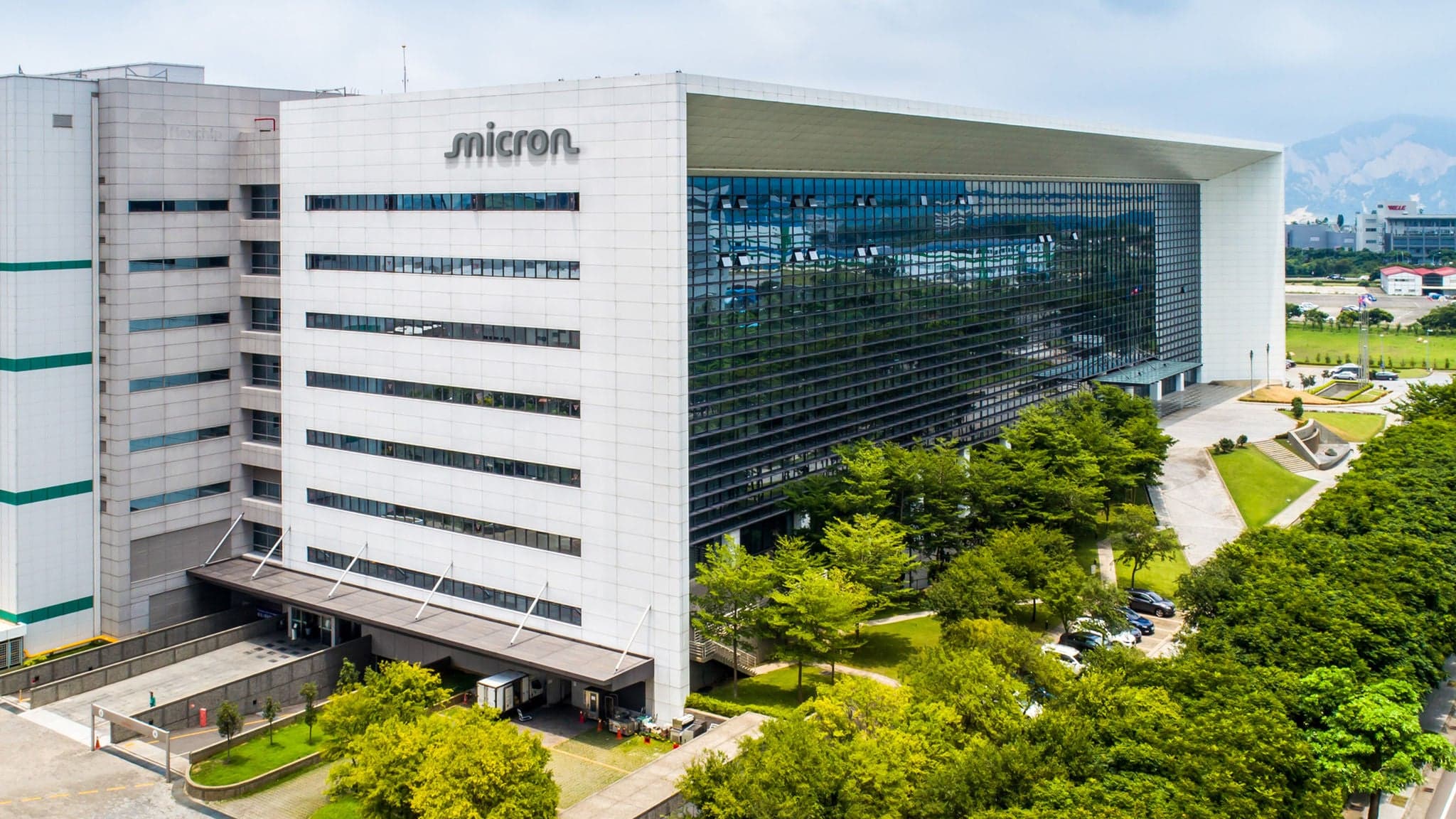 Exterior of Micron's Taichung, Taiwan site, a white and glass-fronted multi-story fab building with the Micron logo